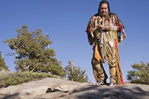 Warrior Prints: A Lakota Native American Indian warrior in full traditional dress standing outdoors on a rock on Donner Summit near