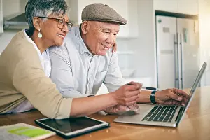 Newspaper Prints: Laptop, happy and mature couple at table in home kitchen
