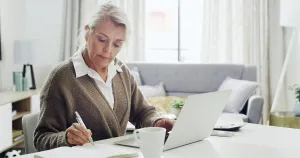 Agenda Prints: Laptop, remote work and writing with woman in living room of home for notes