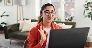 Conversation Prints: Laptop, video call and wave with woman in home living room for discussion or planning