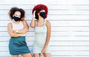 Staring Prints: Two latin women with mask in a carefree attitude on a white background