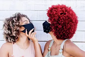 Conversation Prints: Two latin women with mask in a carefree attitude on a white background