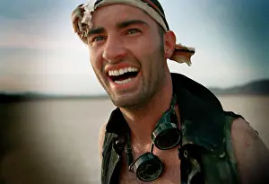30 To 35 Years Prints: Laughing mid adult man wearing a bandana and goggles around his neck while in a desert