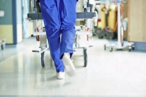 Expect Prints: Legs of medic running with gurney along hospital corridor