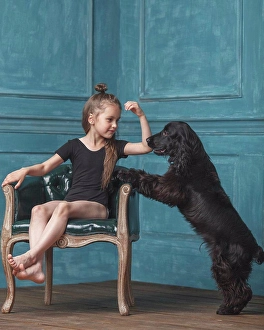Flooring Prints: Full length of girl sitting on antique chair while looking at dog rearing up at home