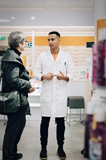 Labcoat Prints: Full length of male pharmacist talking with senior female customer in medical store