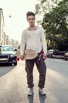 Vertically Prints: Full length portrait confident male high school student with skateboard standing on city street