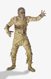 Mystery Prints: Full length portrait of a man dressed as a mummy wrapped in decaying bandages for Halloween making painful movements