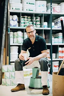 Self Employed Prints: Full length of portrait of salesman sitting on stool in storage room
