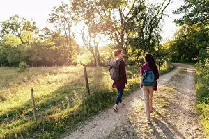 Hike Prints: Full length rear view of mother and daughter hiking on dirt road in forest