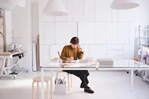 Using Phone Prints: Full length of upholstery worker using mobile phone while writing on note pad in store
