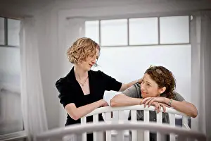 30 To 35 Years Prints: Lesbian couple looking reassuredly at each other while standing beside a cot in a nursery