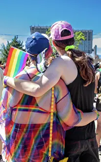 26 29 Years Old Prints: LGBTQ couple at a Pride event, embracing with flags