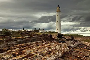 Timber Prints: a lighthouse and piles of logs on the shore, lothian scotland