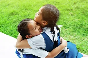 : two little asian girls sisters hugging happy post in school unif