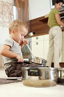 Dekoration Prints: Little boy playing with cooking pots Little boy sitting on carpet in kitchen playing with cooking pots