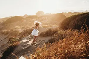Mother And Daughter Prints: Little girl dancing at beach dunes on summer golden sunset