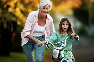 Baby Boomer Prints: Little girl learning to ride her bicycle with the help of her grandmother