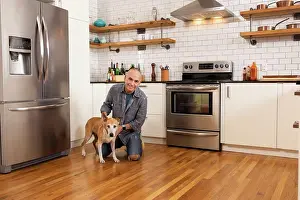 Beginnings Prints: Low angle portrait of man and his pet together in kitchen