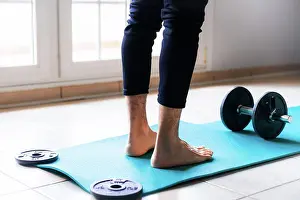 Anonymous Prints: Low angle back view of crop barefooted male athlete in sportswear standing on bright blue sports mat against black