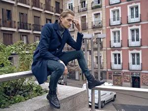 Ponder Prints: Low angle side view of serious elegant young male in stylish coat leaning on hand