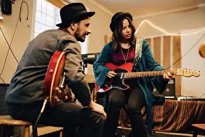 Arts Culture And Entertainment Prints: Low angle view of male and female friends playing guitars at recording studio