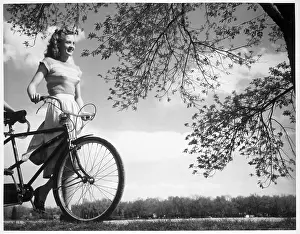 Bicycle Prints: Low angle view of a teenage girl walking with a bicycle