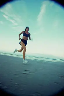 Sports Shoe Prints: Low angle view of a young woman running on the beach