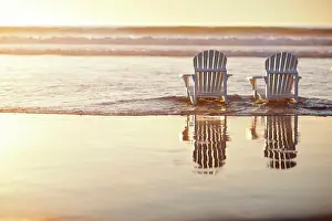 Seas Prints: Low tide washing over two deck chairs on a beach at sunset