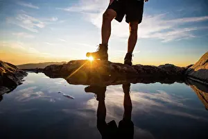 Lower Prints: Lower half view of hiker wearing boots on mountain summit