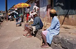 Eastern Prints: Madagascar, Ambositra, A Group Of Local People Sat On A Wall Waiting At The Side Of The Road
