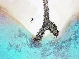 35 To 40 Years Prints: Maldives, Kaafu Atoll, Aerial view of man lying alone on sandy coastal beach of Huraa island