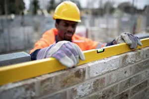 Inspecting Prints: Male construction worker using level tool on brick wall