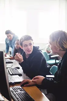 Student Prints: Male high school students discussing while sitting at desk using computers in classroom