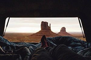 Road Trip Prints: Male legs and feet relaxing inside four wheel drive with view of sandstone buttes from car boot