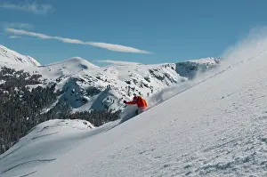 Diagonal Prints: A male skier wearing a bright orange jacket makes a series of powder turns on a powder day at a Mountain Resort