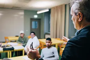 Instruction Prints: Male teacher gesturing while teaching students in classroom