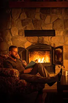 Glow Prints: Man (40) sitting by a warm open fire at a log cabin ski chalet in Mont Tremblant