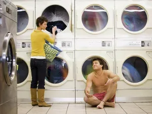 Spouses Prints: Man in boxers sleeping at Laundromat with woman removing clothing from dryer