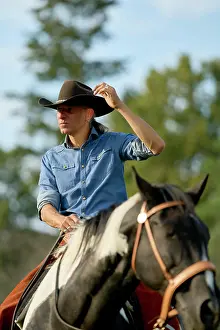 Rural Prints: A man in a cowboy hat and blue denim shirt rides a horse while looking into the distance