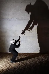 50 54 Years Prints: Man cowering from tall ominous shadow on wall