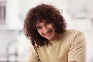 Smart Prints: A MAN WITH CURLY HAIR HAPPILY SITTING AND LOOKING AT CAMERA