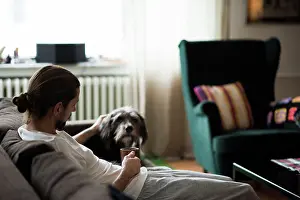 One Mid Adult Man Only Prints: Man with dachshund relaxing on sofa