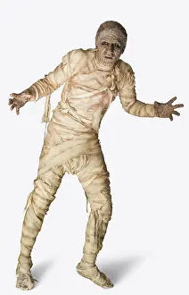 Mystery Prints: Man dressed up as a mummy for Halloween making stiff arm movements against a white background