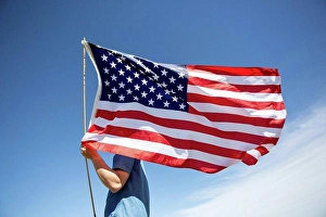 Identity Prints: Man holding American flag under blue sky