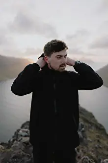 Adjusting Prints: Man with hooded jacket on hill above river, Klakkur, Klaksvik, Faroe Islands