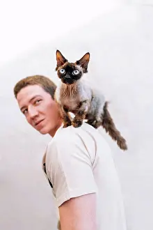 Animal Prints: Man looking at cat on shoulder by wall