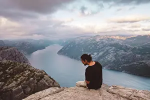 Hike Prints: Man looking down curious sitting in rock at edge of cliff at Preikestolen, Norway