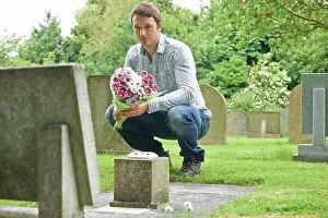 Visiting Prints: Man Placing Flowers By Headstone In Cemetery