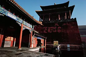 Chinese Culture Prints: Man riding a bicycle through a pool of water in front of an ancient Chinese building